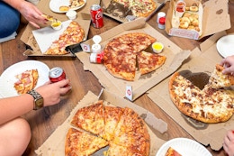 a group of people eating pizza from dominoes