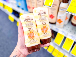 a hand holding two bottles of sunscreen
