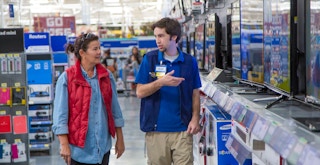 A Walmart employee talking to a customer in the electronics department
