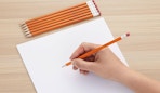 a stack of pencils in front of a blank piece of paper 