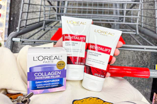 person holding loreal collagen moisturizer and 2 loreal revitalift cleansers