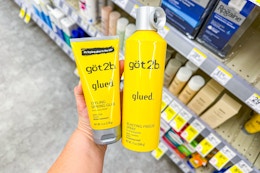 person holding got2b hair styling products by the shelf