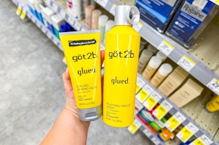 person holding got2b hair styling products by the shelf