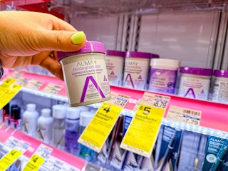 person holding almay makeup remover pads in front of a display