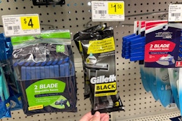 hand touching a pack of gillette black razors at dollar general
