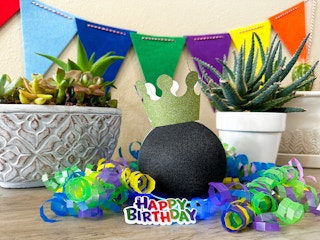 alexa echo dot with a birthday hat and birthday decor sitting on a table 