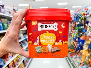 hand holding tub of milk bone dog treats