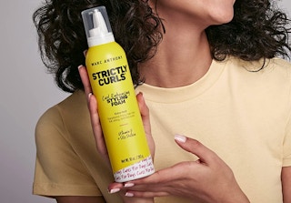 person holding a can of marc anthony strictly curls hair foam