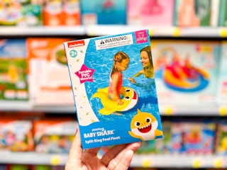 person holding a baby shark pool float in front of a shelf