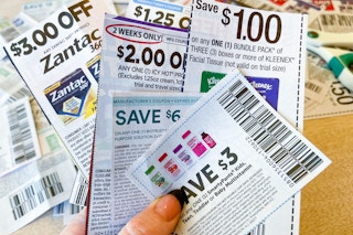a person's hand holding a bunch of coupons