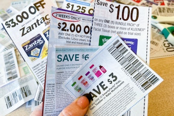 a person's hand holding a bunch of coupons