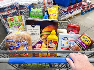 Someone pushing a cart filled with grilling essentials at Walmart