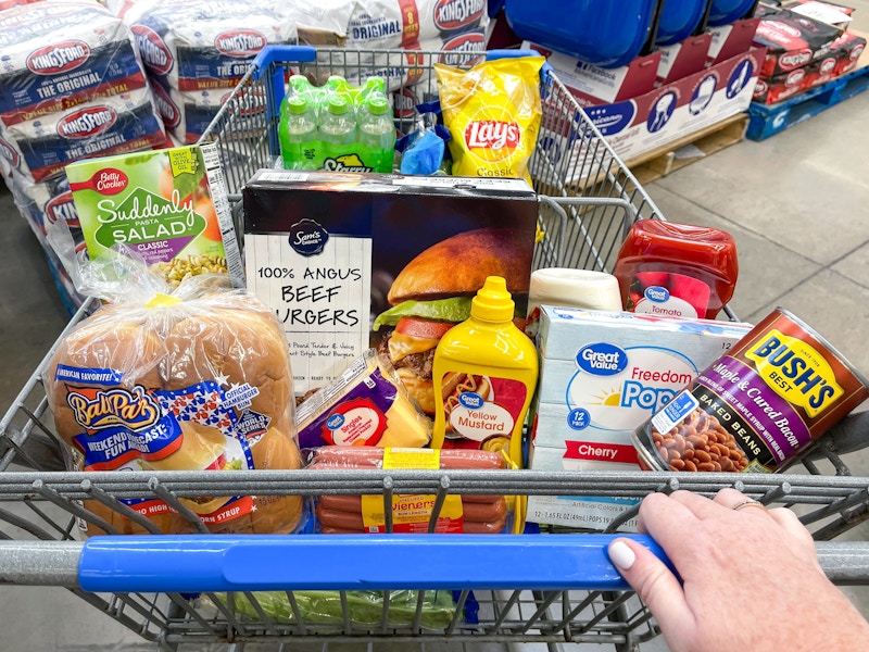 Someone pushing a cart filled with grilling essentials at Walmart