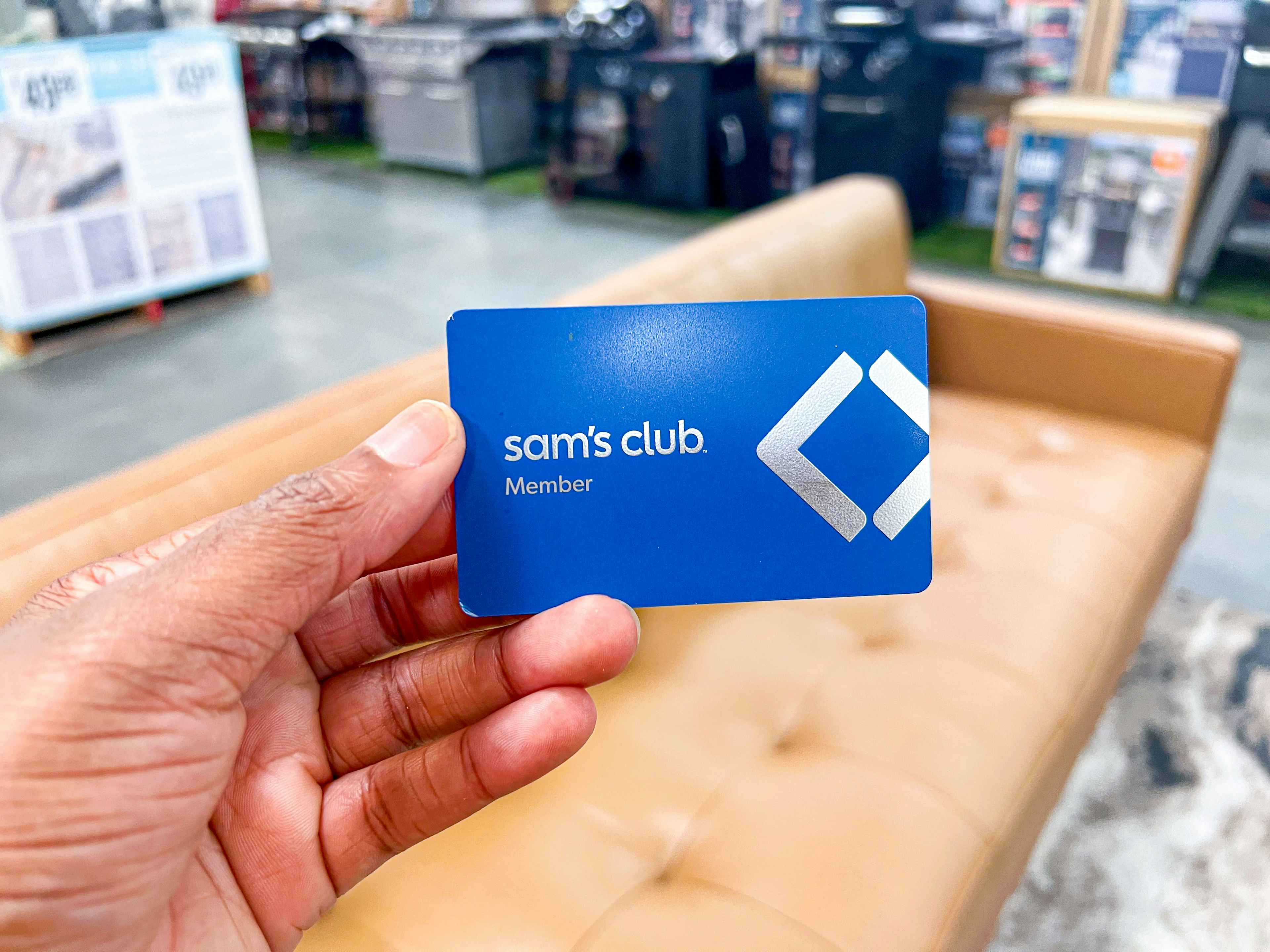 Hand holding a Sam's Club Card in front of Furniture