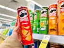 person holding a container of pringles in front of the display