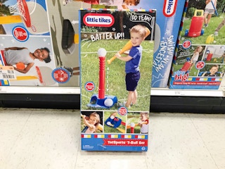 Little Tikes t ball set inside box, leaned up against the display of other Little Tikes boxes