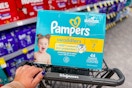 person pushing a cart with a box of pampers diapers in it