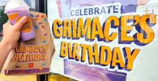 person holding grimaces birthday meal bag and shake near mcdonalds signage