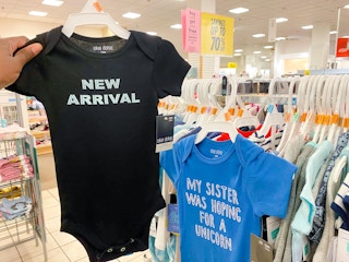 hand holding baby bodysuit on hanger