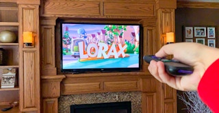 a person pointing a tv remote at a tv with the lorax playing