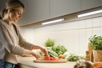 A woman prepares a vegetable plate with her work space lit by the under cabinet lights.