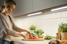 A woman prepares a vegetable plate with her work space lit by the under cabinet lights.
