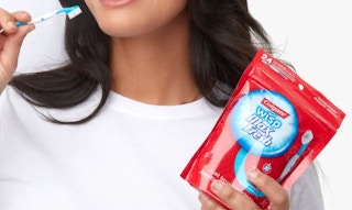 person using colgate wisp travel toothbrushes and holding a package of colgate wisps