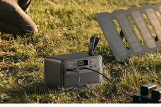 portable power station charging items on grassy area