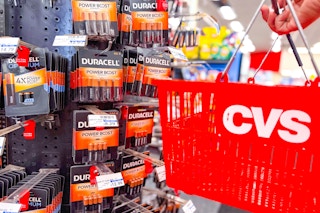 person holding a cvs shopping basket by the duracell batteries display