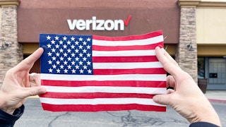 a person holding an american flag in front of a verizon store