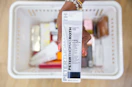 a hand holding a skincare in packaging over a shopping basket 