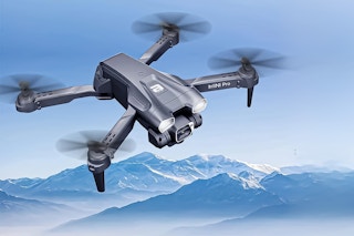 Lifestyle image of the BEEPRINCESS mini drone flying in the sky over mountains 