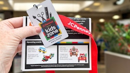 a person holding up a jcp kids workshop badge and flier in front of store
