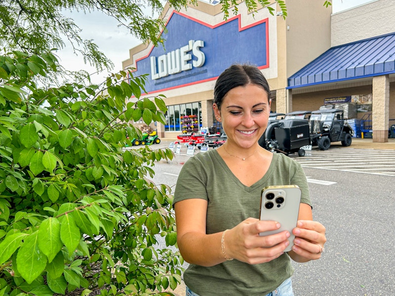 a person standing outside of lowes smiling while on their phone