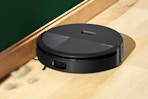 Lifestyle image of the iRobot Roomba 2020 Vacuum/Mop cleaning up dust bunnies 