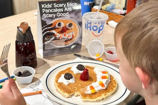 a child holding a fork about to eat a ihop scary pancake