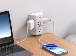 a phone and laptop plugged into an outlet extender in a wall