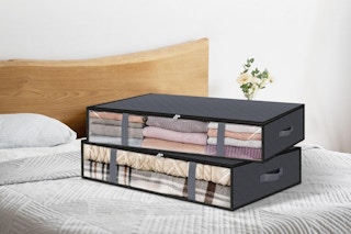 Two storage bags with clear windows in the side sit on a bed.