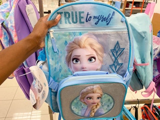 a frozen backpack being held on a rack full of backpacks in kohls