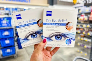person holding 2 boxes of zeiss eye masks in an aisle