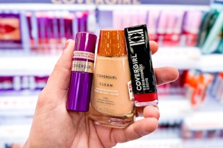 hand holding three covergirl makeup products