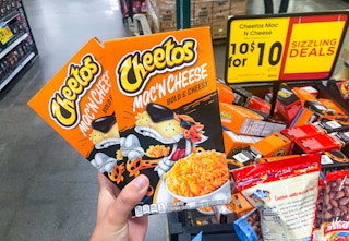 hand holding boxes of mac n cheese in front of sale sign