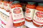 person grabbing a jar of rao's marinara sauce off the shelf