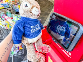person holding a large peter rabbit plush by a scanner