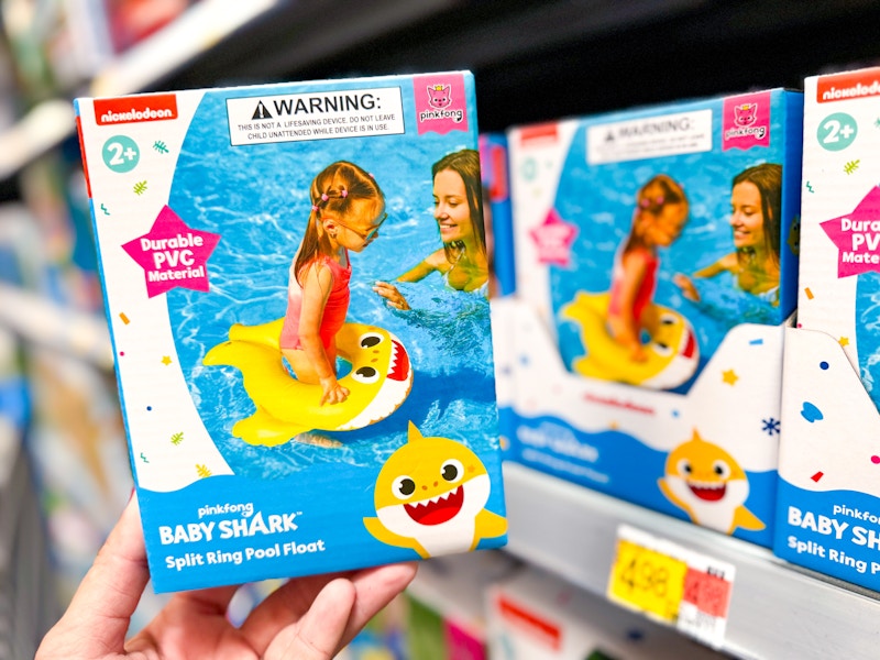 person holding a baby shark pool float in front of a shelf