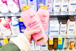 hand hodling two ogx body wash bottles