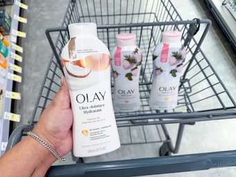 hand holding olay body wash and body wash in cart