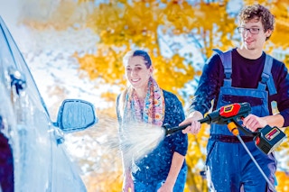 Lifestyle image of a Nexpow Cordless Pressure Washer being used by two adults to wash a car