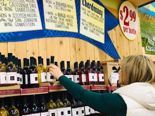 Person pulling white wine from a store shelf
