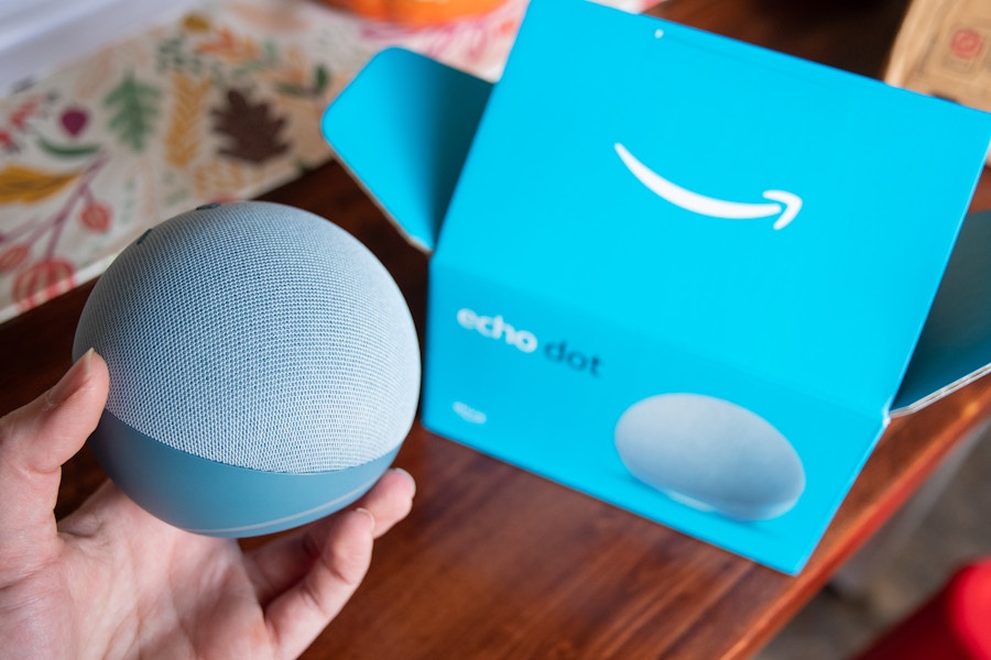 A person holding an amazon echo 4th generation device next to the box it came in.